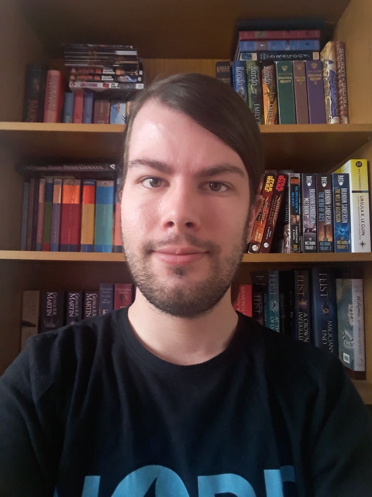 A picture of myself in front of my bookshelf.